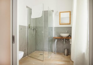 A modern bathroom with a glass-enclosed shower, a white sink, and a mirror on the wall.