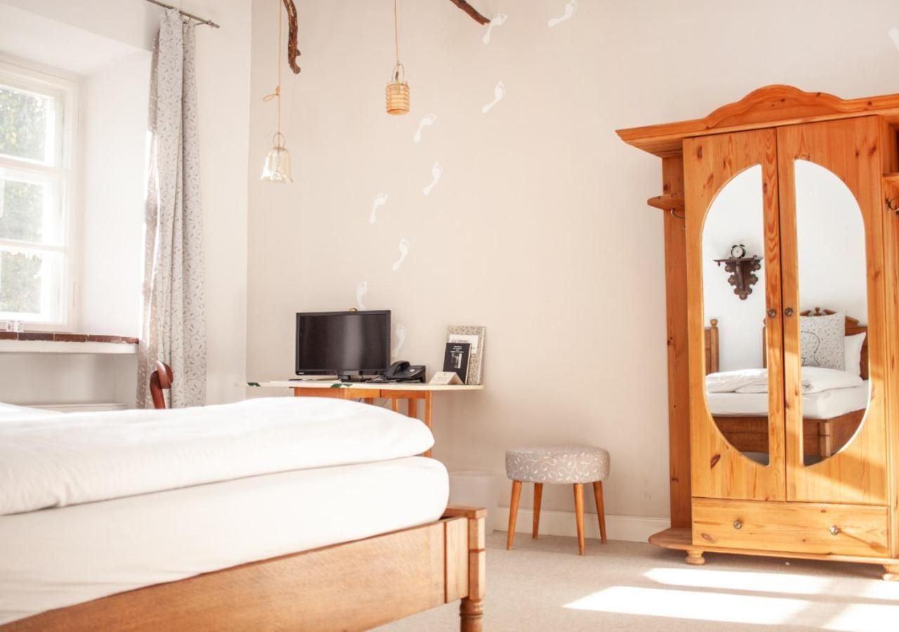 Une chambre à coucher avec un lit, un bureau avec un ordinateur, une armoire et une fenêtre.