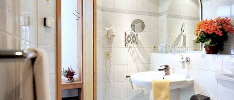 A bathroom with a sink, mirror, towel rack, and a potted plant.