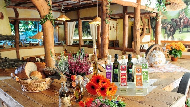 A rustic wooden table with bread, flowers, and bottles of local spirits. - Kelten-Hotel (Unterbreizbach)