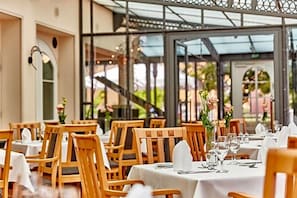 A restaurant with wooden chairs and tables, covered patio area, and outdoor seating.