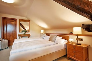 A hotel room with a large bed, a wooden nightstand, a mirror, and a radiator.