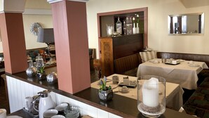 L’intérieur d’un restaurant, avec un bar, des tables et un grand miroir décoratif.