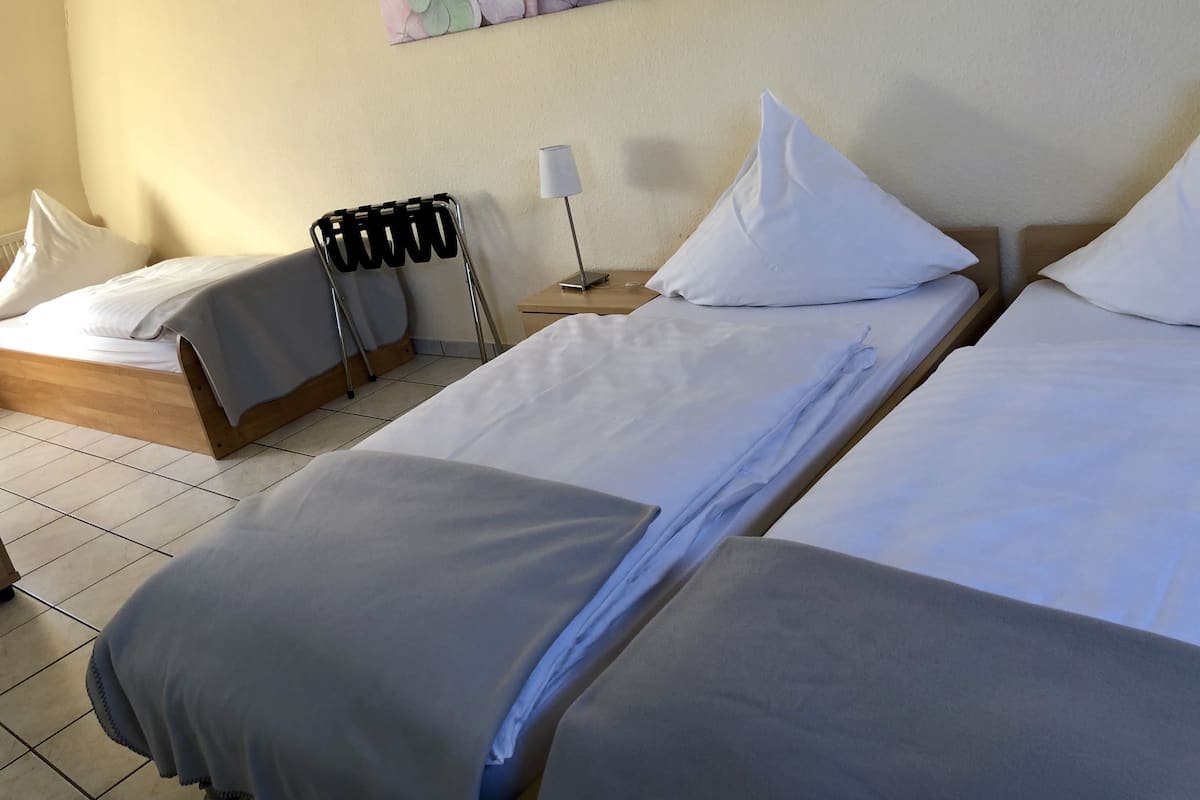 A hotel room with two beds, a nightstand, a lamp, and a wall-mounted artwork.