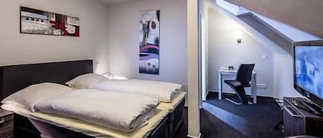 A modern hotel room with two beds, a desk, a chair, and a television.