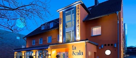 Un hotel con una entrada destacada, un espacio al aire libre cubierto y una fachada bien iluminada.