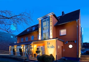 Un hotel con una entrada destacada, un espacio al aire libre cubierto y una fachada bien iluminada.