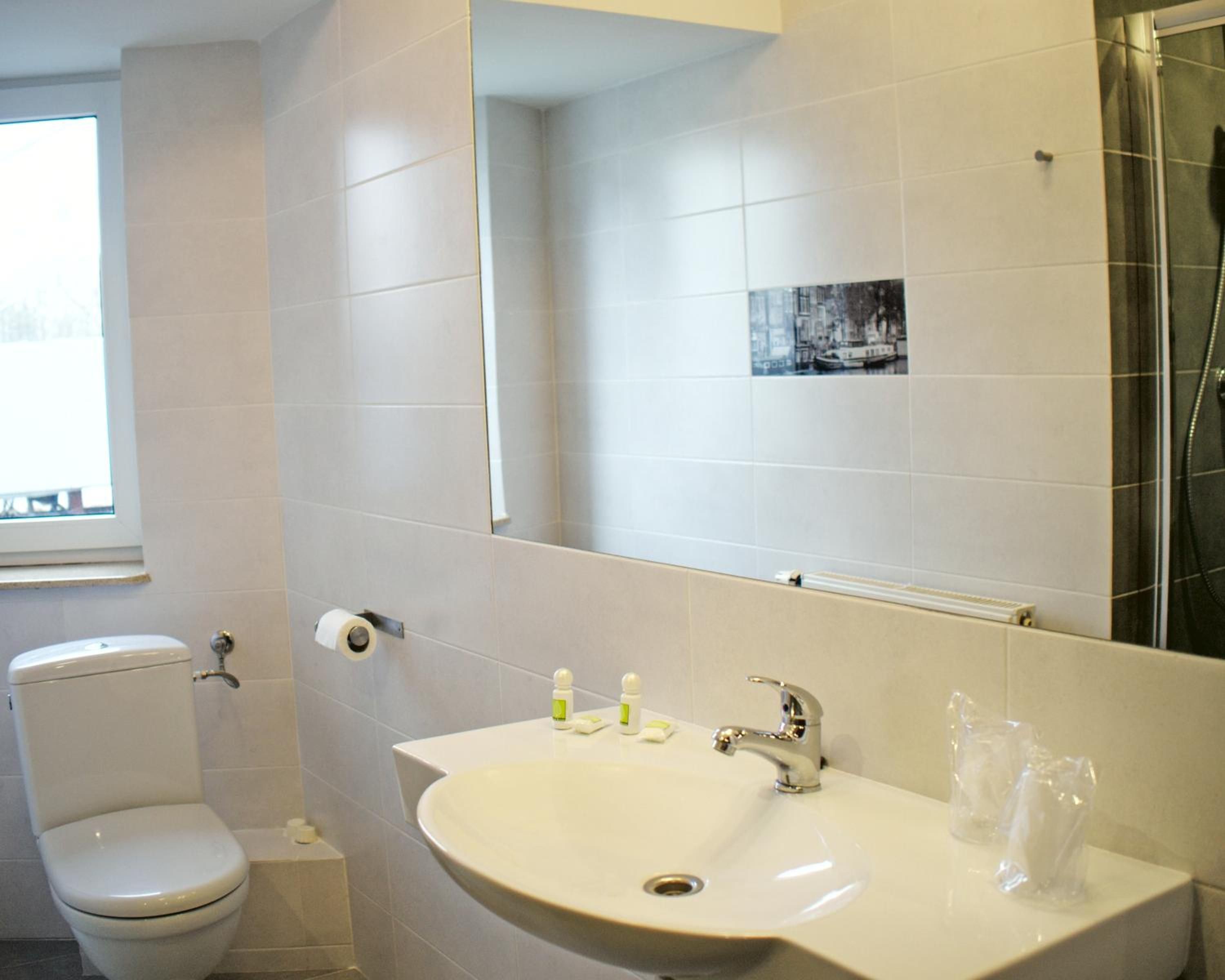 A bathroom with a toilet, sink, mirror, and shower.