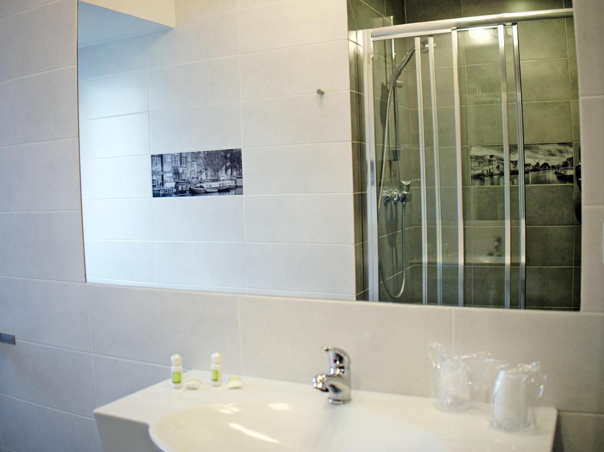 A bathroom with a white sink, a glass shower enclosure, and a black-and-white photo on the wall.