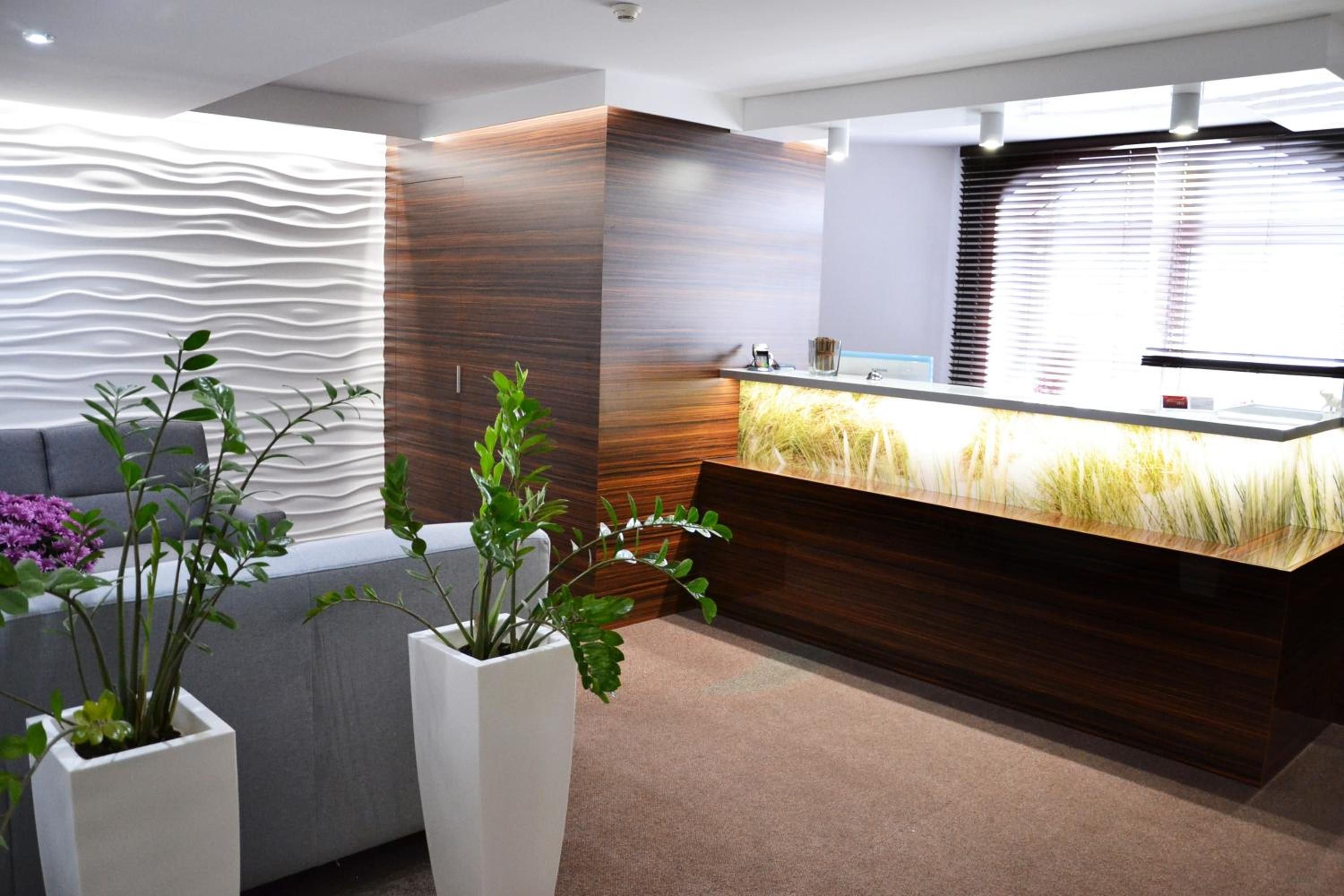A reception area with a modern design, including a reception desk, a sofa, and potted plants.