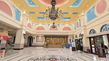 En rummelig lobby med en imponerende lysekrone, en reception og et mønstret gulv.