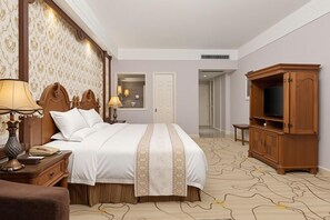A hotel room with a large bed, wooden headboard, bedside lamps, a television cabinet, and a patterned carpet. - Lianjiang Libo Hotel (Lianjiang)