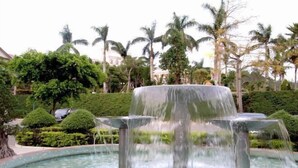A fountain with water cascading down multiple tiers, surrounded by lush greenery and palm trees. - Lianjiang Libo Hotel (Lianjiang)