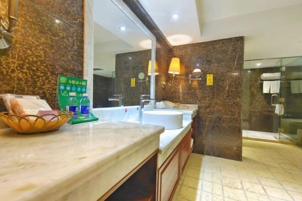 Un baño moderno con tocador de mármol, lavamanos dobles y cabina de ducha con mampara de vidrio.
