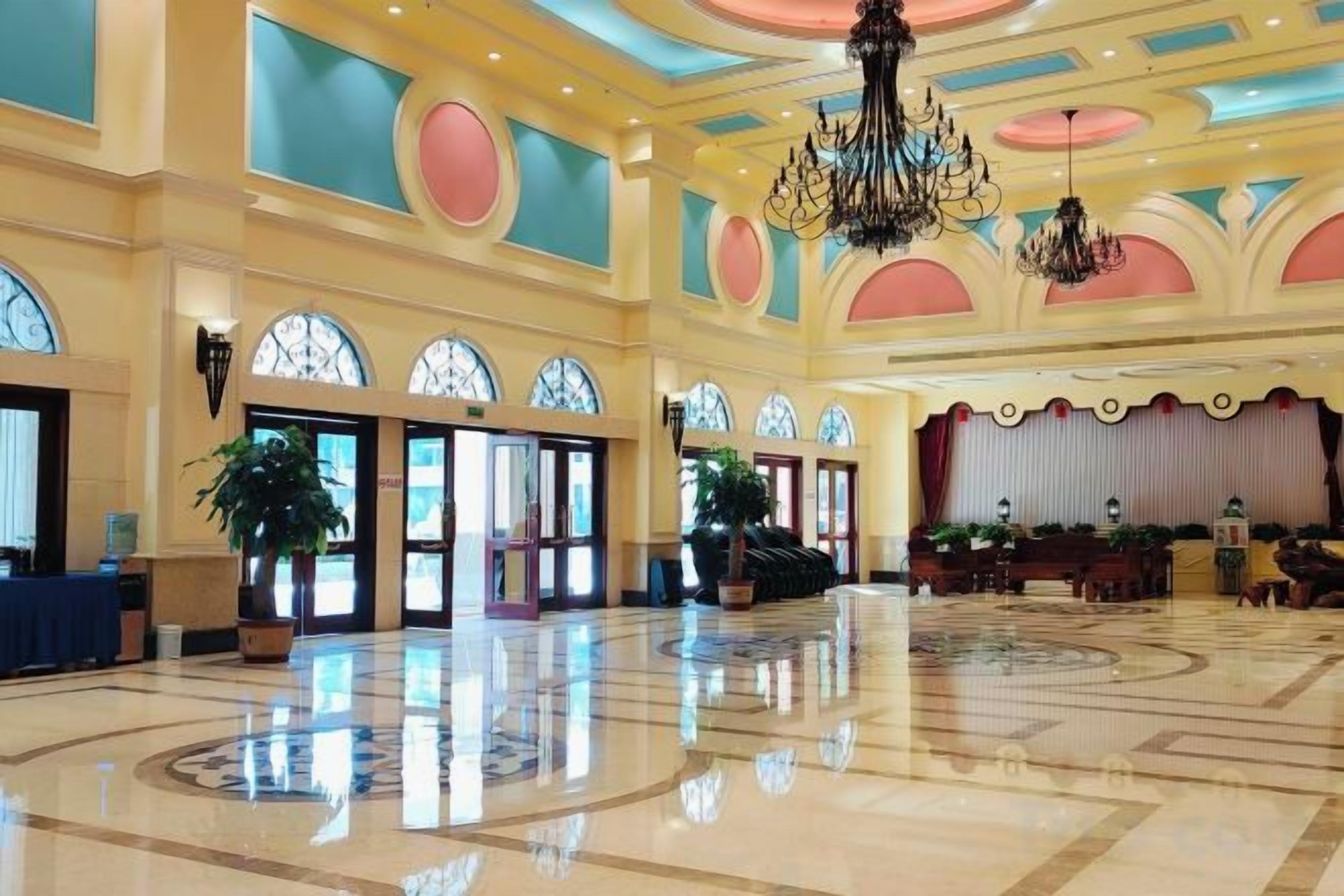 A spacious lobby with a high ceiling, large windows, and a chandelier.