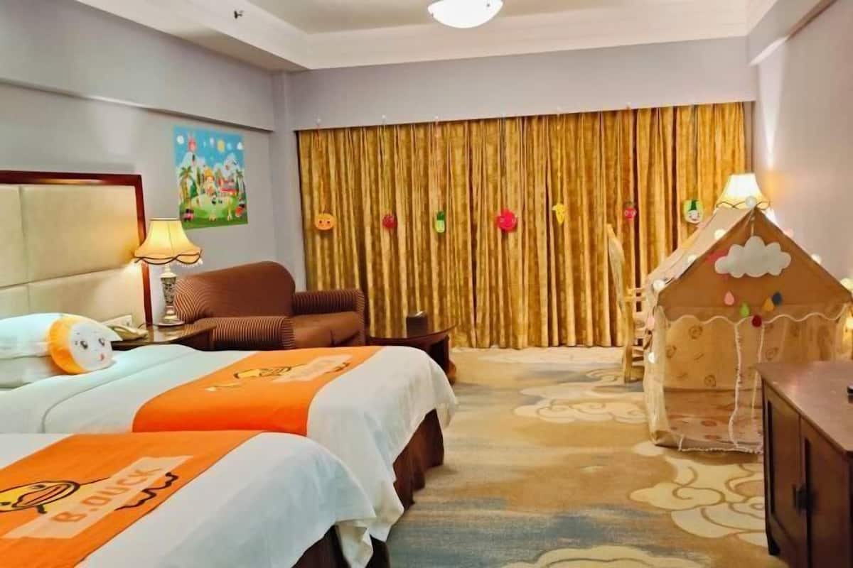 A hotel room with two beds, a sofa, a wooden dresser, a lamp, and a decorative wall hanging.