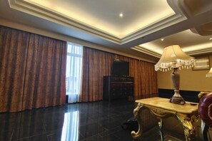 A spacious hotel room with a large window, a flat-screen TV, a decorative lamp, and a classic armchair. - Lianjiang Libo Hotel (Lianjiang)