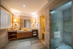 Un baño moderno con tocador de madera, cabina de ducha de vidrio y un inodoro a la vista.