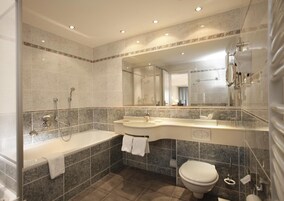 Un baño moderno con bañera, un espejo grande y un inodoro.