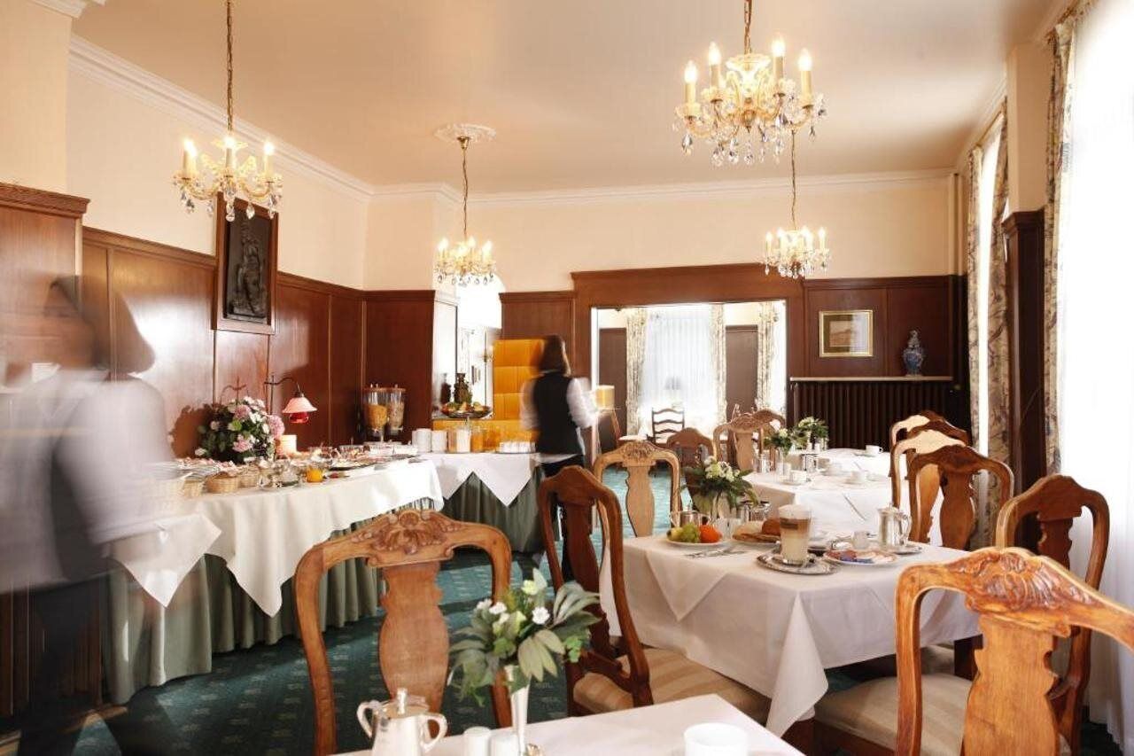Ein stilvolles Esszimmer mit mehreren Tischen, Kristalllüstern und Holzvertäfelung.