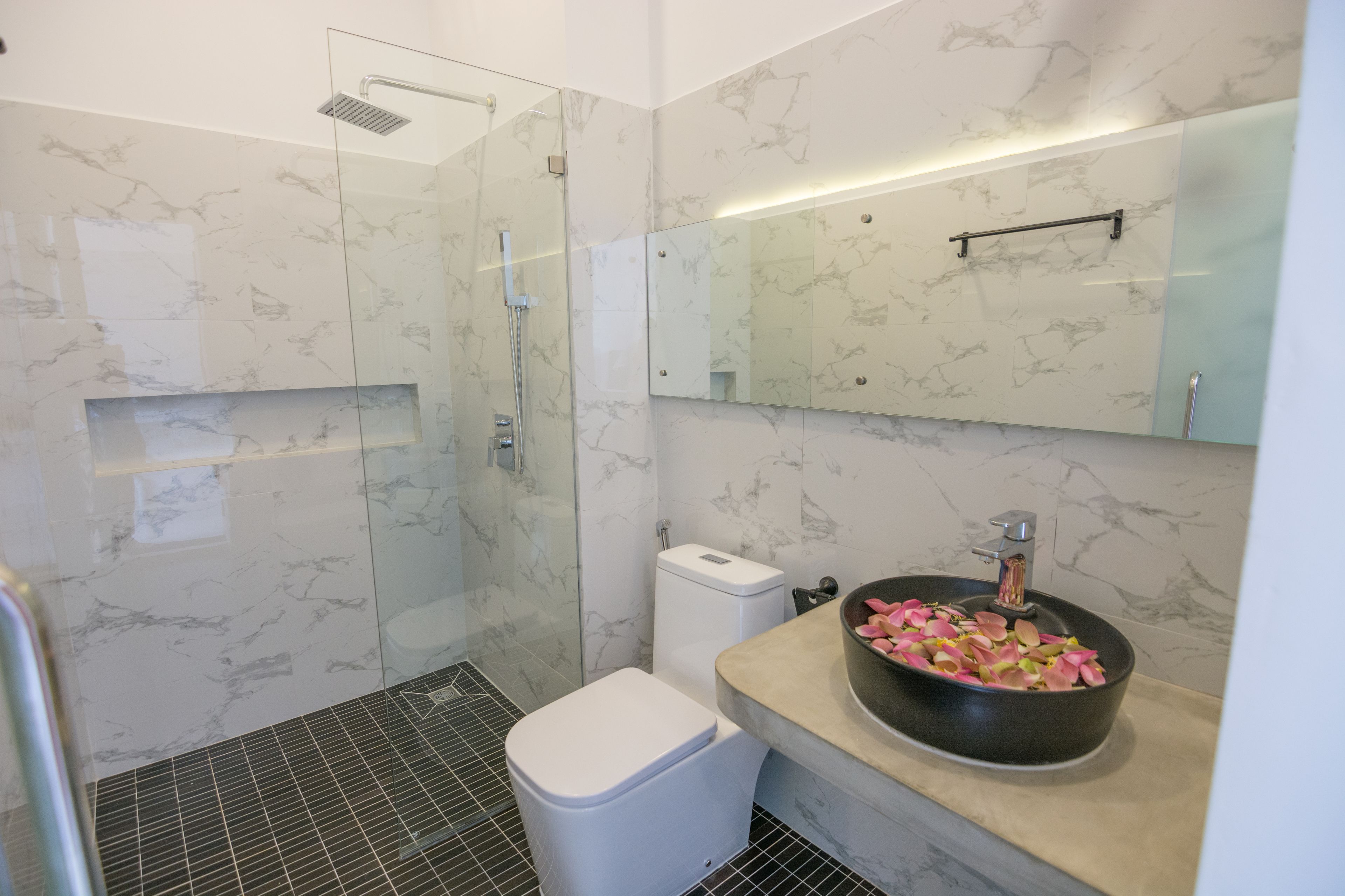 Un baño moderno con cabina de ducha de vidrio, inodoro y lavabo con encimera de mármol.