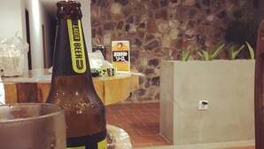 A bottle of beer on a table with a stone wall and a sign in the background.