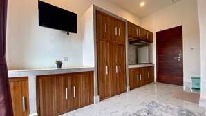 A modern kitchen with wooden cabinets, a built-in oven, and a flat-screen TV mounted on the wall.