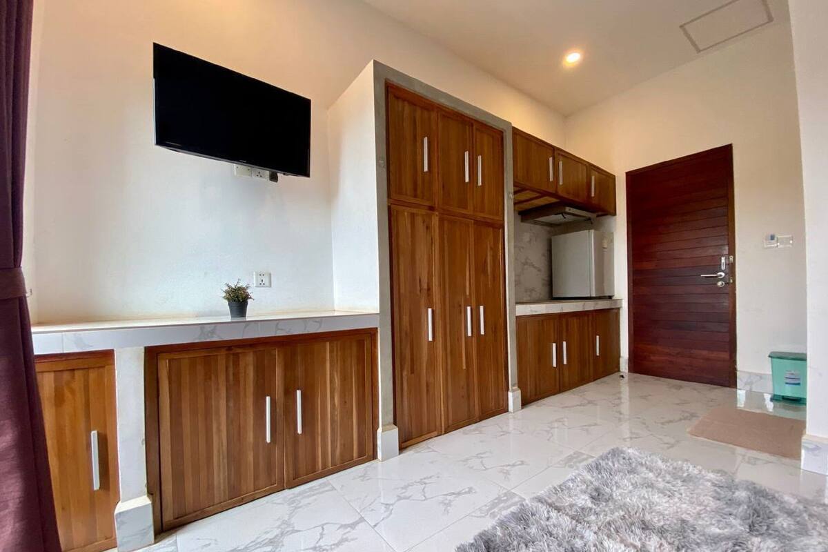 Una cocina moderna con armarios de madera, horno empotrado y televisor de pantalla plana en la pared.
