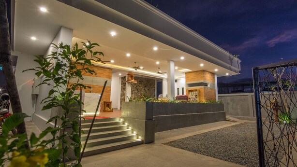 A modern house with a covered porch, outdoor seating, and a staircase leading to the entrance.