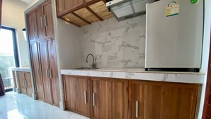 A kitchen with wooden cabinets, a marble countertop, and a white refrigerator.