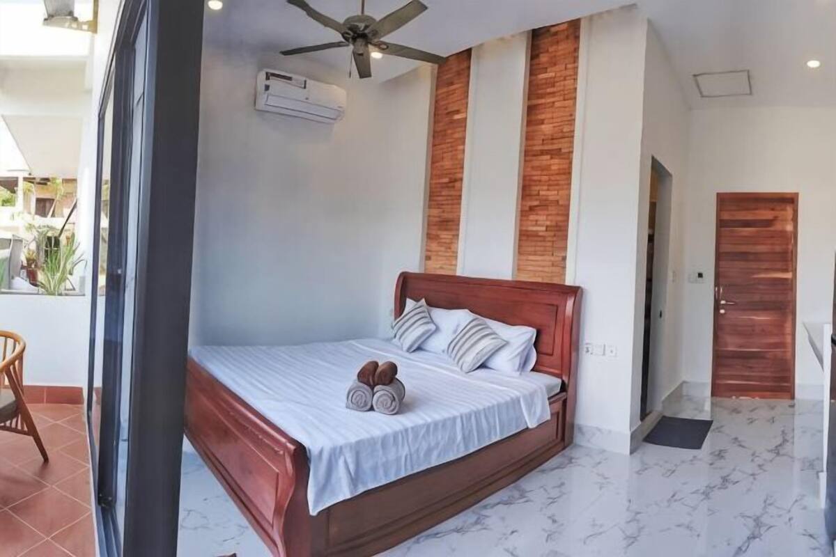 Un dormitorio con cama de madera, ropa de cama blanca y ventilador de techo.