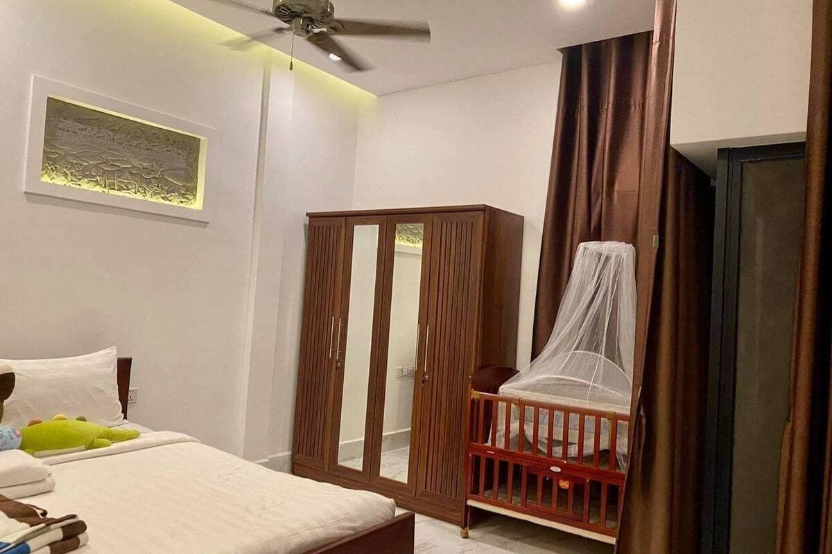 Un dormitorio con cama, armario, cuna con dosel y ventilador de techo.