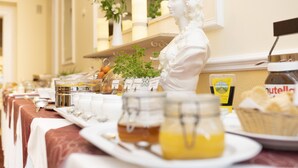 A buffet setup with a white statue, various food items, and condiments.