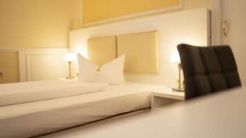 Una habitación de hotel con una cama bien hecha, dos lámparas de noche y una silla.
