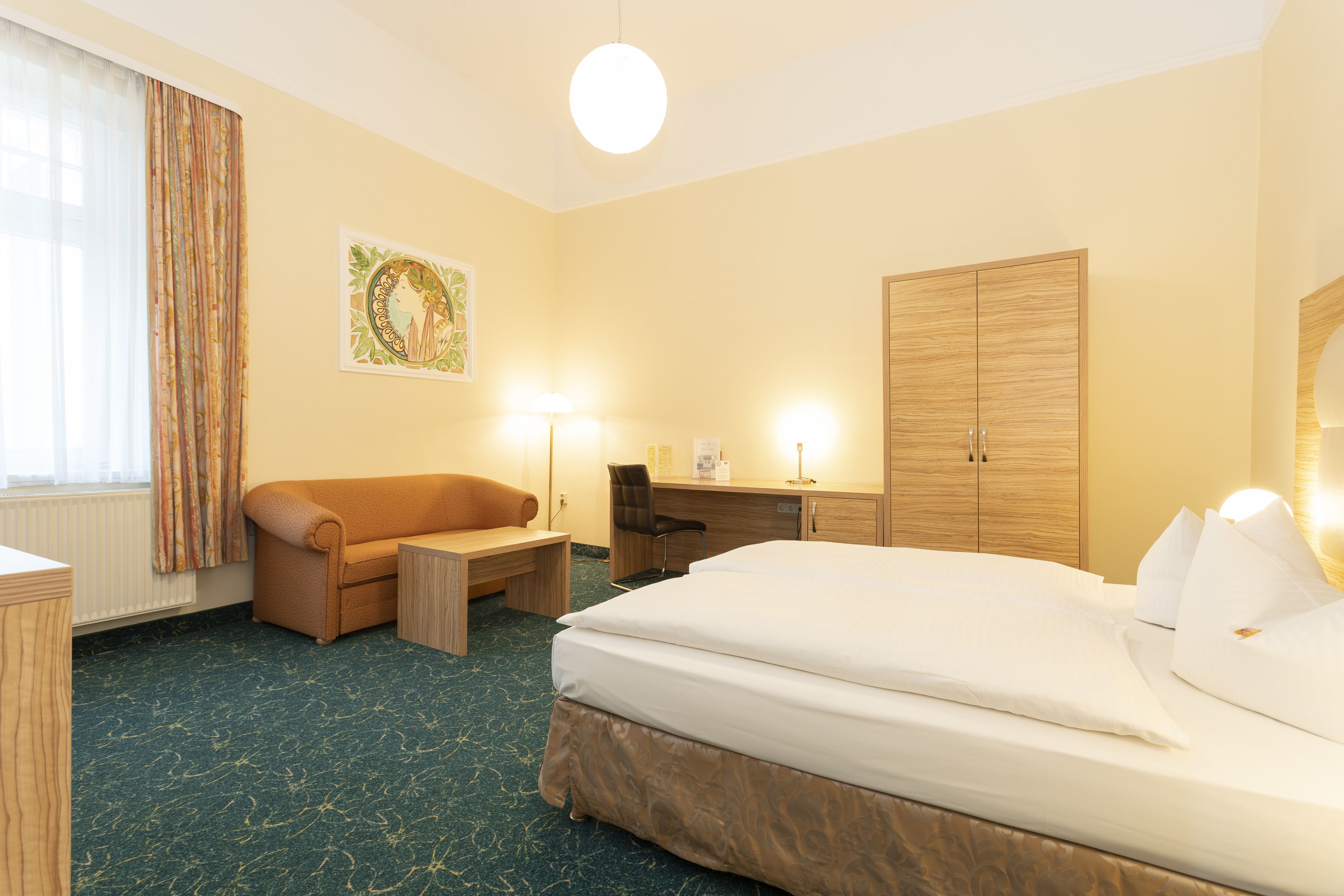 Une chambre d’hôtel comprenant un lit, un bureau, une chaise, une armoire et une fenêtre avec des rideaux.