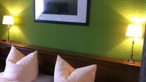 Une chambre d’hôtel avec un mur vert, deux lits avec du linge de lit blanc et deux lampes de chevet.