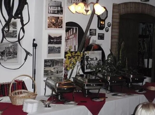 Um quarto com uma mesa posta para refeições, um rádio antigo e uma parede decorada com fotografias emolduradas.