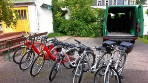 Une rangée de vélos garés, un fourgon vert et, au fond, un bâtiment avec une porte jaune.