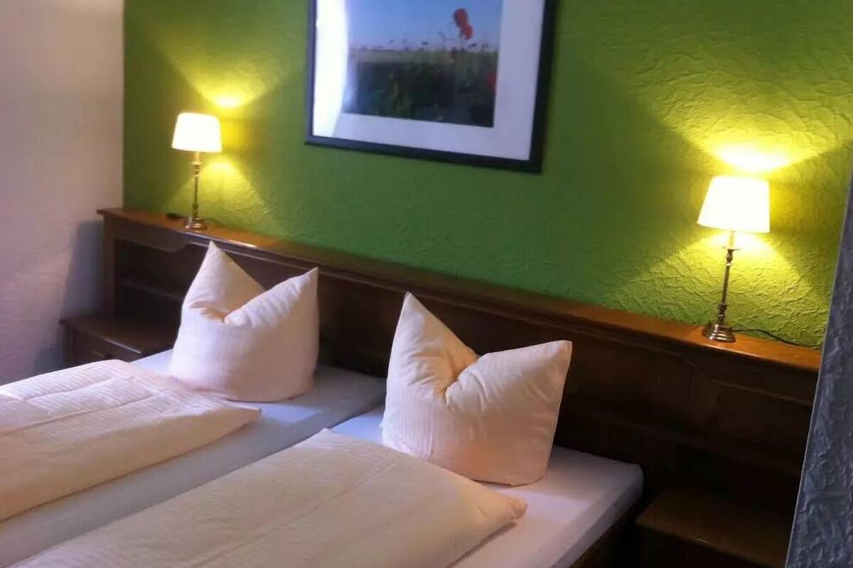 Une chambre d’hôtel avec deux lits, chacun équipé de draps et d’oreillers blancs, ainsi que de deux lampes de chevet.