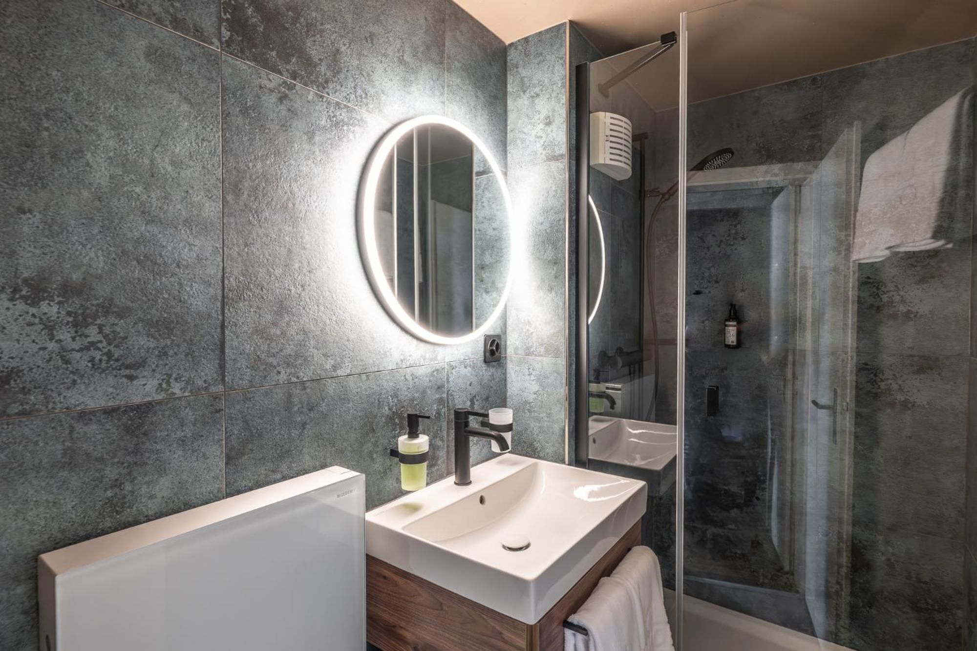 Een moderne badkamer met een grote spiegel, twee wasbakken en een douchehoek.