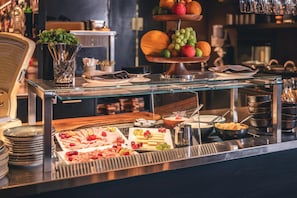 A buffet setup with various food items and a fruit display.