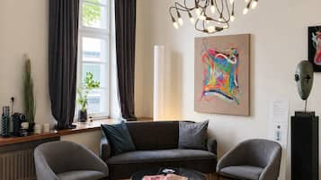 A modern living room with a sofa, two armchairs, a coffee table, and a unique light fixture.