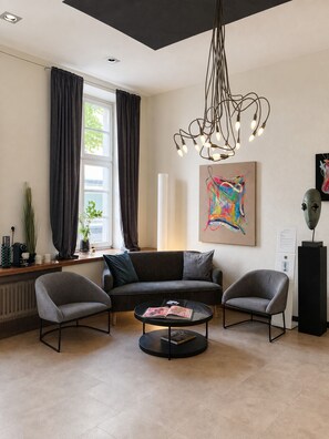 Una sala de estar moderna con sofá, dos sillones, una mesa de centro y una lámpara de techo original.