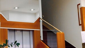 Una escalera con barandillas de madera y un ascensor instalado en la pared.