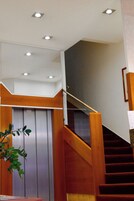 Una escalera con barandillas de madera y una puerta de ascensor de metal.