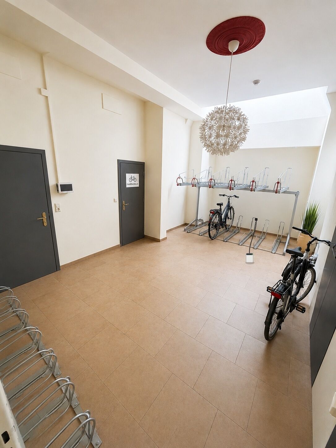 A spacious room with a bicycle rack, a door marked 'FABRIKATORIUM,' and a ceiling light fixture.