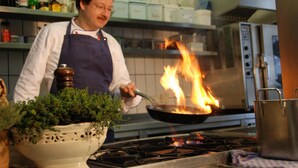 Un chef cocinando con llamas en una cocina.