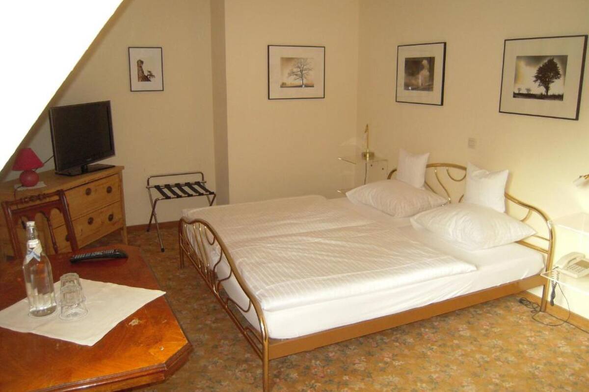 A bedroom with a bed, a dresser, a television, and a lamp.