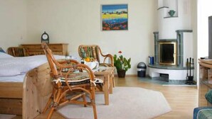 Um quarto aconchegante com uma cama, uma cadeira de madeira, uma mesa com uma planta e uma lareira.