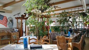 Uma sala de jantar com móveis de madeira, uma grande bandeira americana e um ventilador de teto.